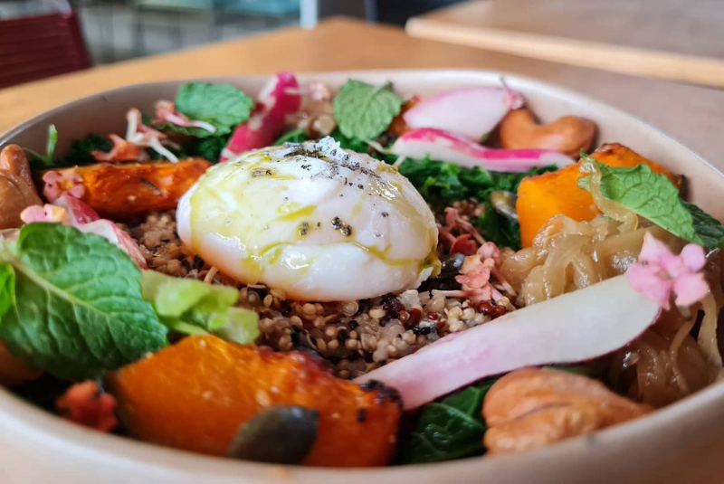 Quinoa bowl with organic vegetables poached egg and fresh herbs